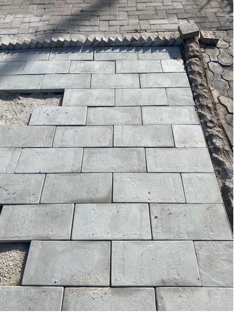 Grey paving being laid in a brick pattern